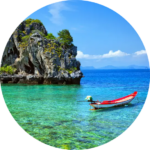 Traditional wooden boat floating on crystal-clear turquoise waters beside rocky islands in the Andaman Islands.